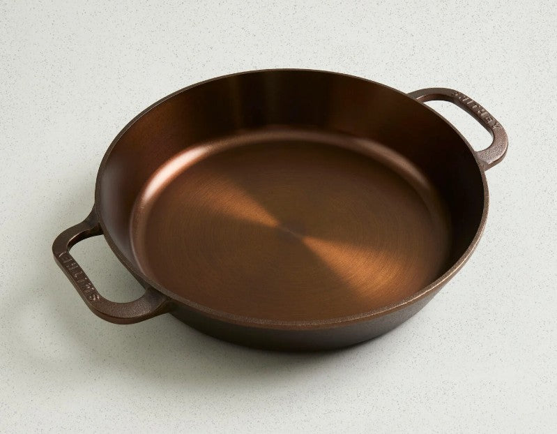 Bronze-colored cast iron skillet on a light gray background