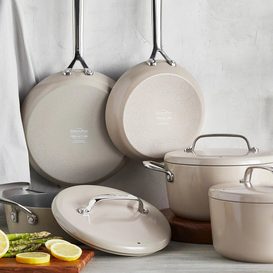 A set Green Pan GP5  ceramic nonstick cookware with mirror handles, including pots and pans with their respective lids, displayed on a kitchen counter.