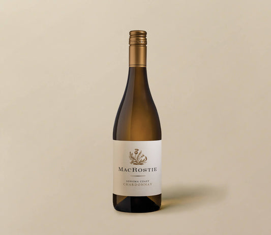 A single bottle of MacRostie Chardonnay wine on a plain beige background. The bottle is dark glass with a gold foil capsule and a white label featuring the MacRostie brand name and a small botanical illustration.