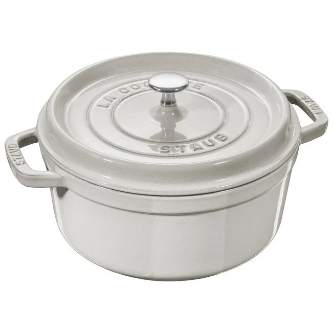 A white truffle-colored STAUB cocotte with a round shape and a heavy lid, made of cast iron, displayed against a plain background.