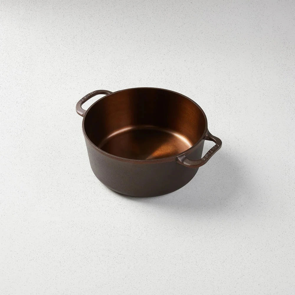 A brown 5.5 Qt Dutch Oven with a polished interior surface and two handles on a light background.