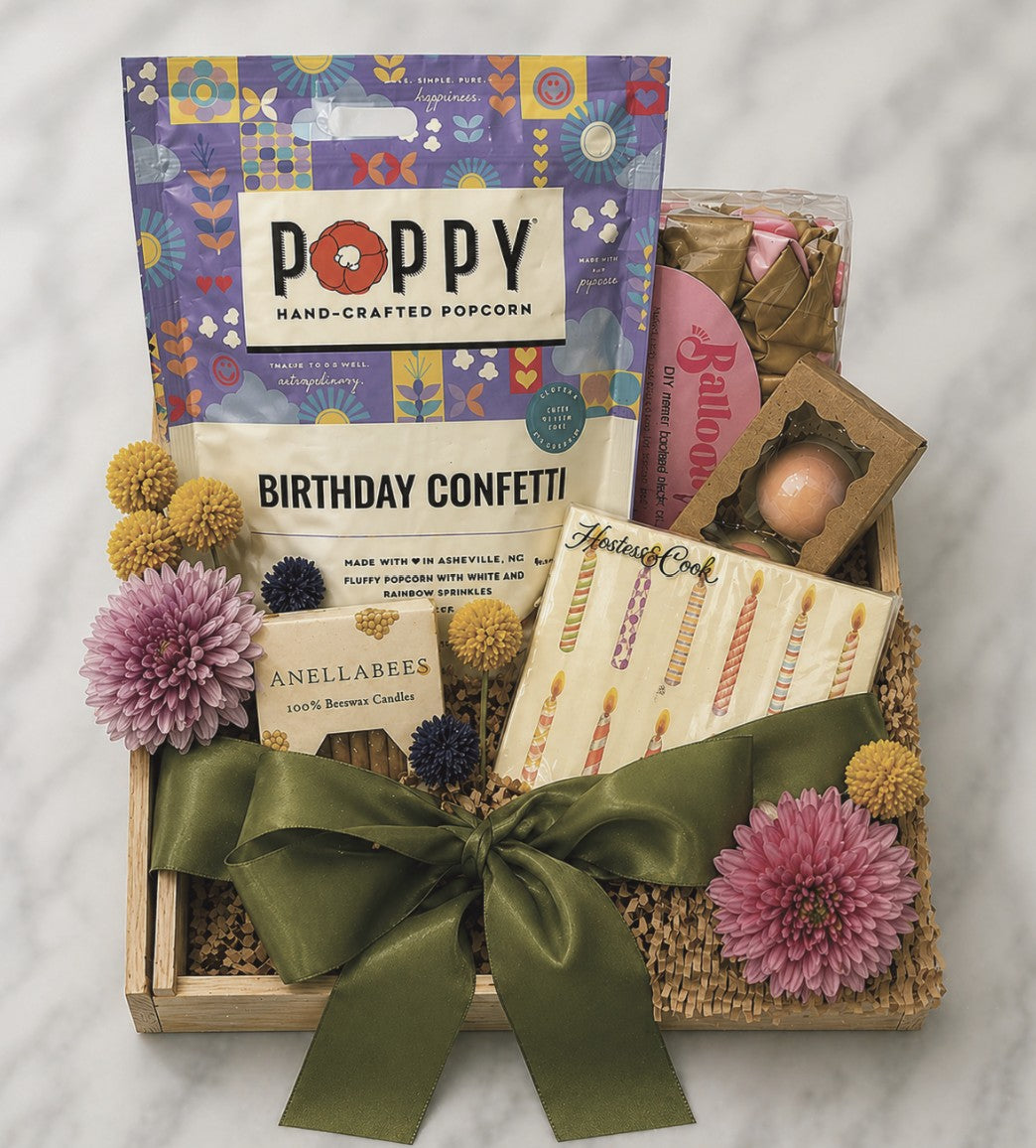 DASH Home + Kitchen Gift basket with birthday confetti, candles, and a box of Poppy hand-crafted popcorn on a marble surface.