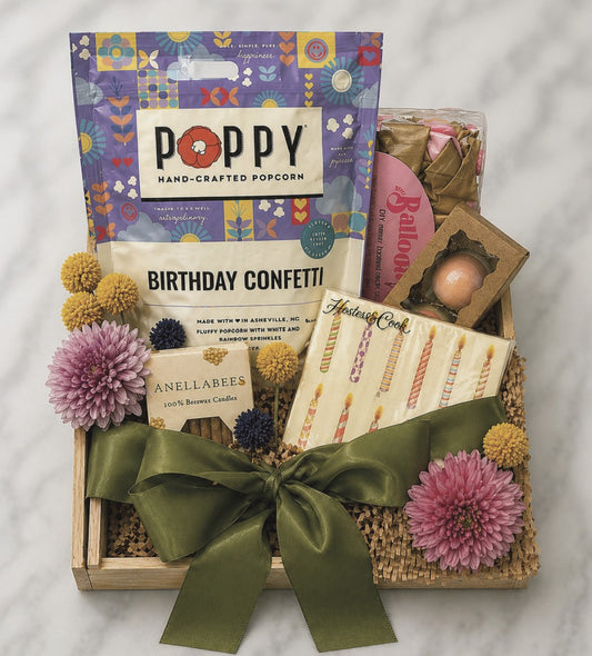 DASH Home + Kitchen Gift basket with birthday confetti, candles, and a box of Poppy hand-crafted popcorn on a marble surface.